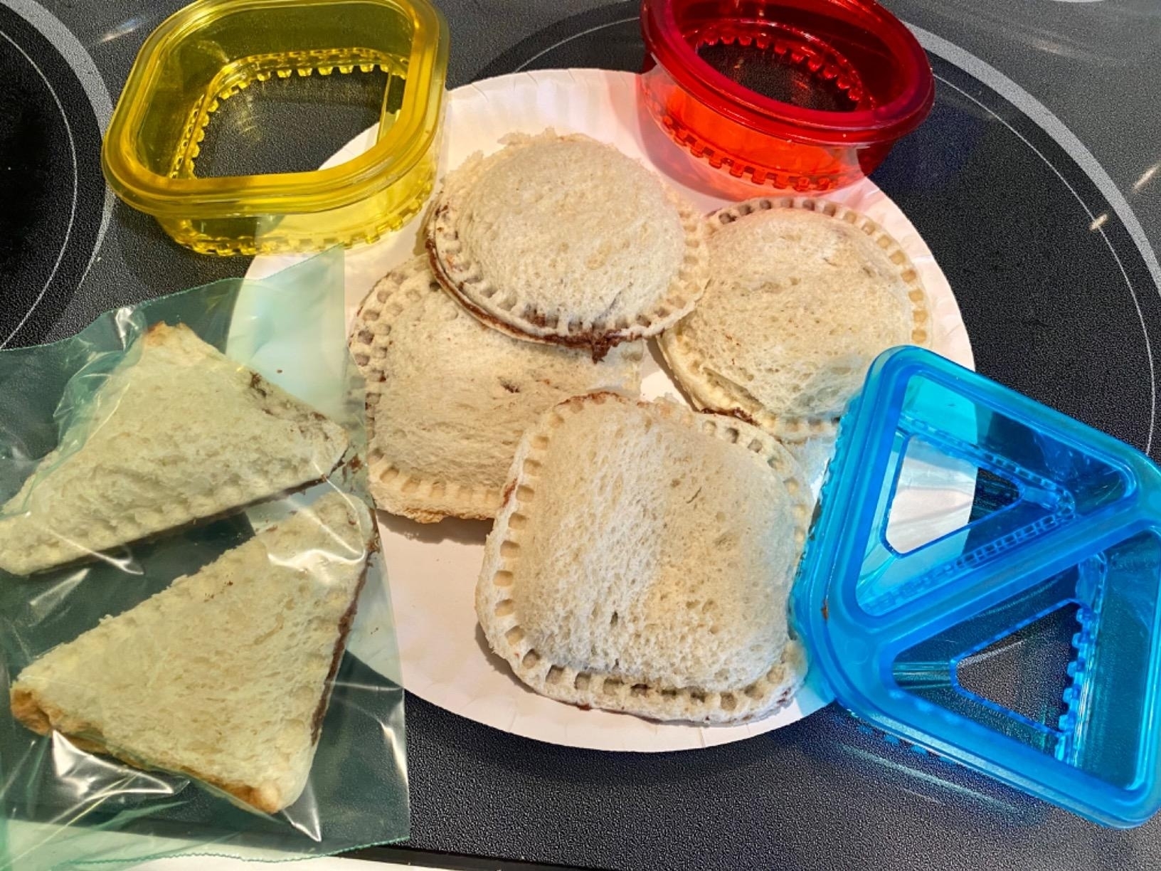 the cut sandwiches on a plate next to the different shaped cutters