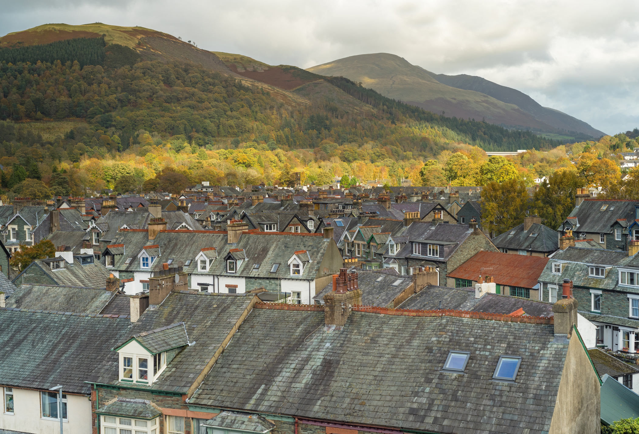 Rooftops of a town in the foreground; in the background, green hills