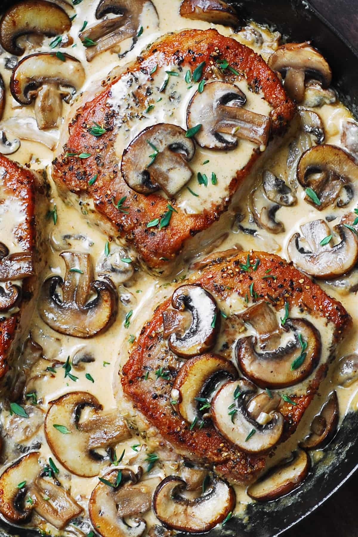 cooked pork chops in a pan with a creamy mushroom sauce