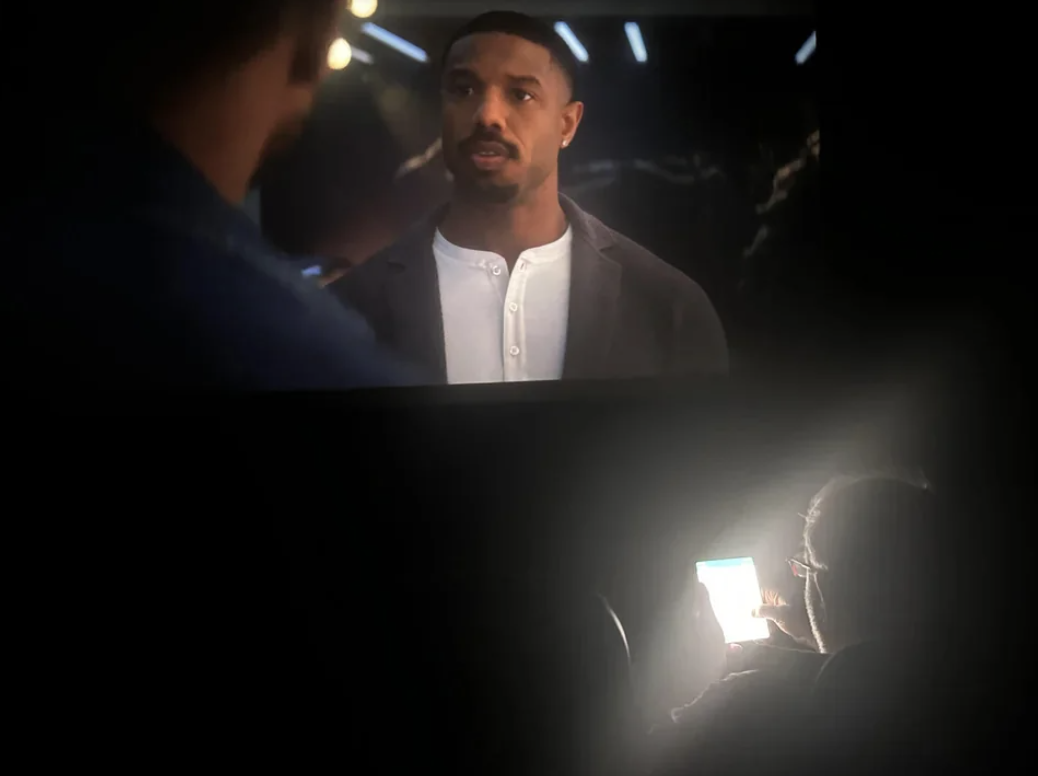 person&#x27;s face lit by their phone in a theater