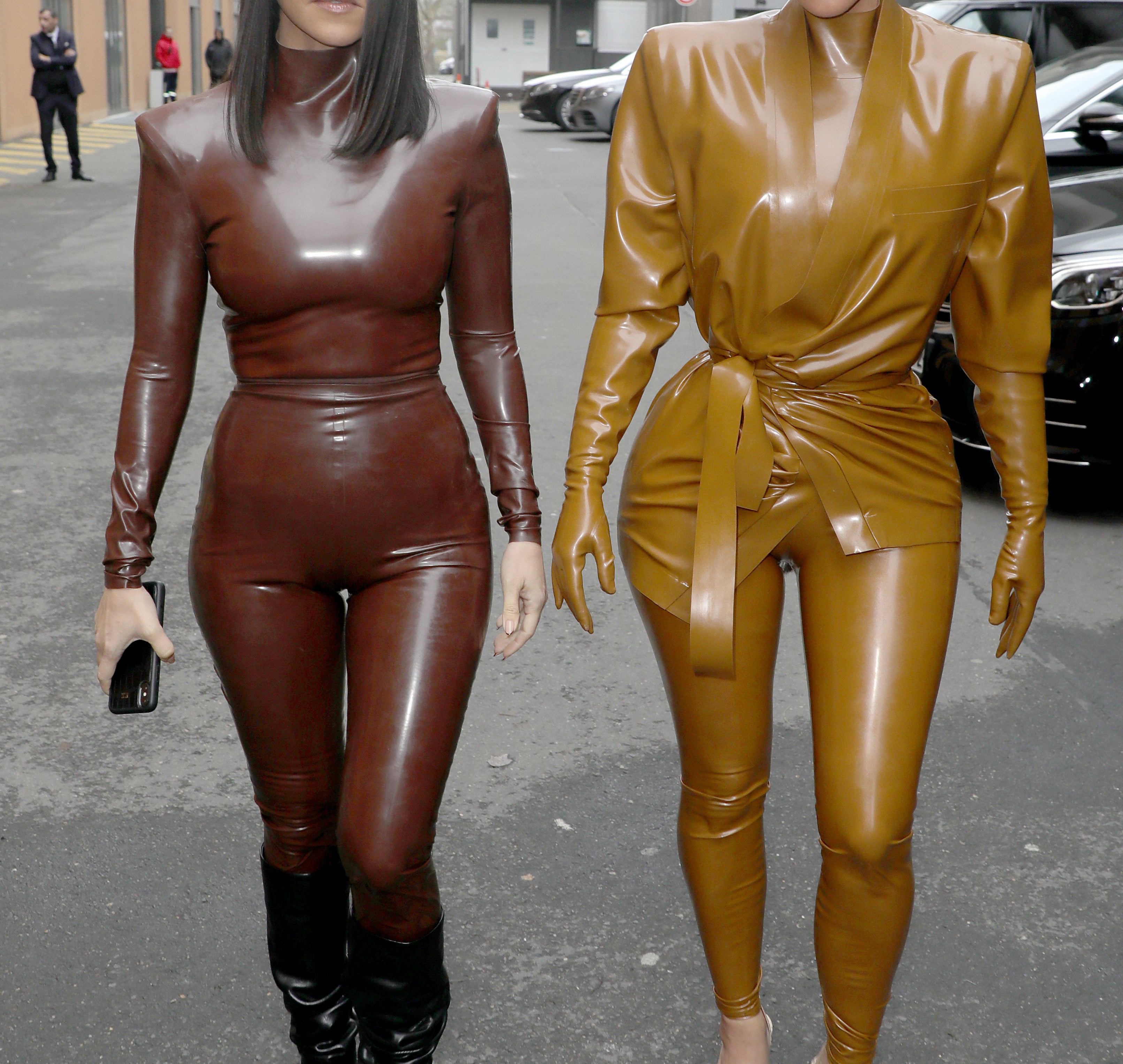 Kourtney and Kim walking on the street and wearing skintight, shiny bodysuit outfits