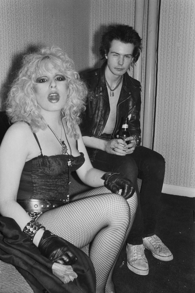 nancy in fishnet tighs and corset top and sid wearing a leather jacket with no shirt underneath