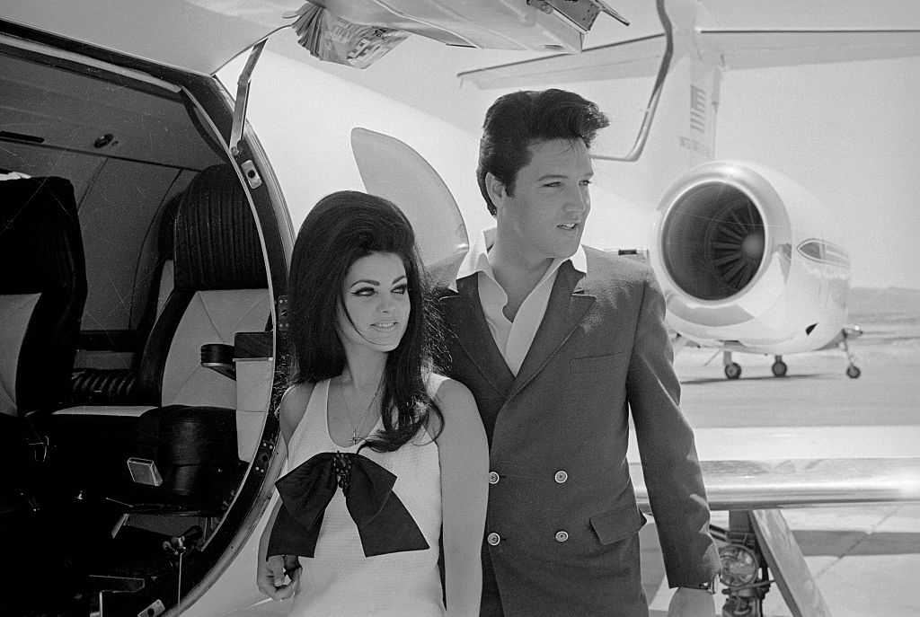 elvis in a suit and priscilla in a dress with a large bow in the front