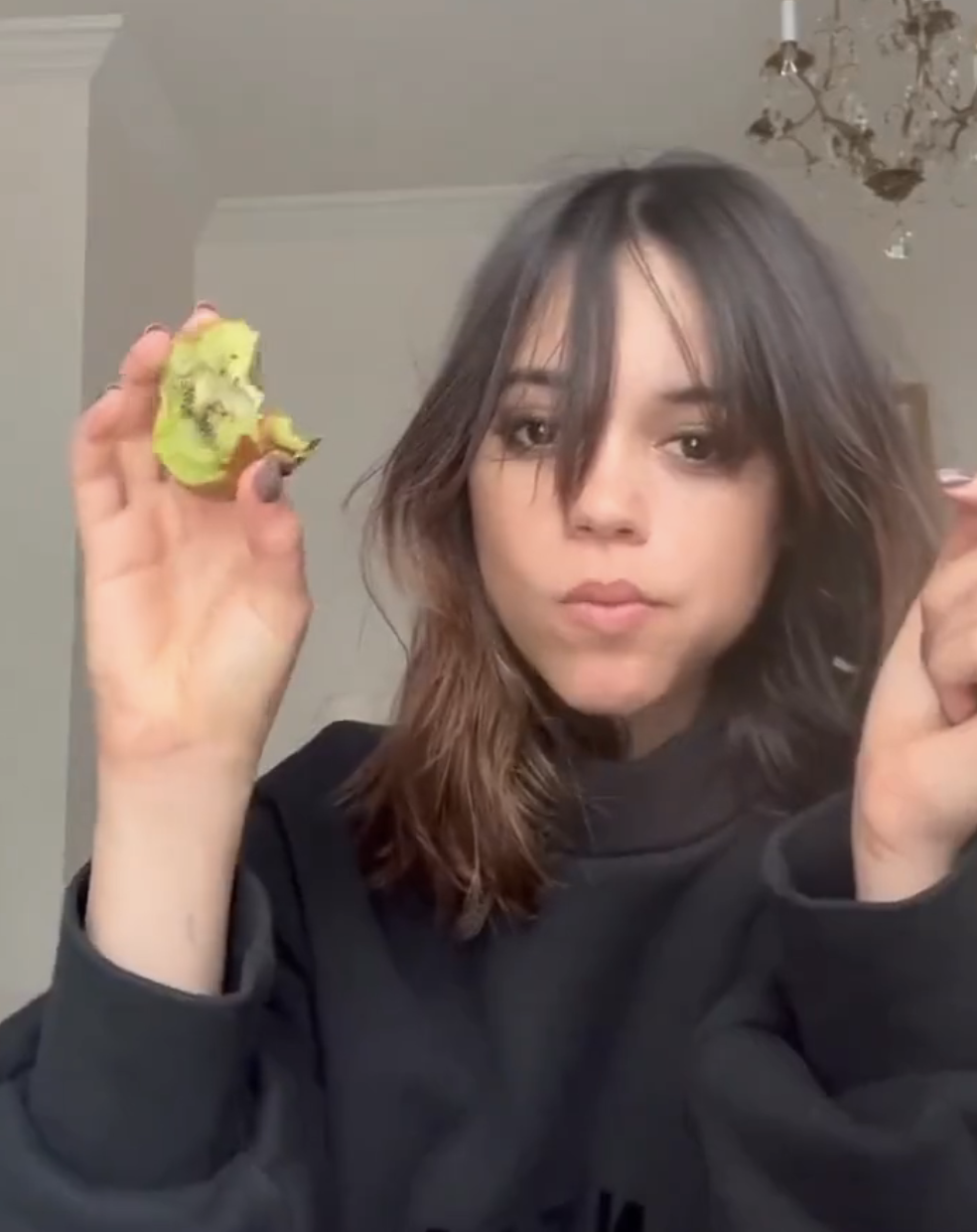 Closeup of Jenna Ortega eating a kiwi