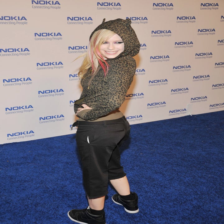 Avril Lavigne on the blue carpet wearing an animal print hoodie.