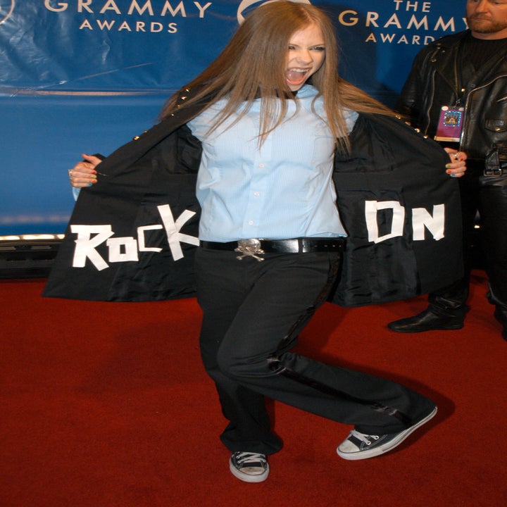 Avril Lavigne on the red carpet with an opened suit jacket that reads "ROCK ON."