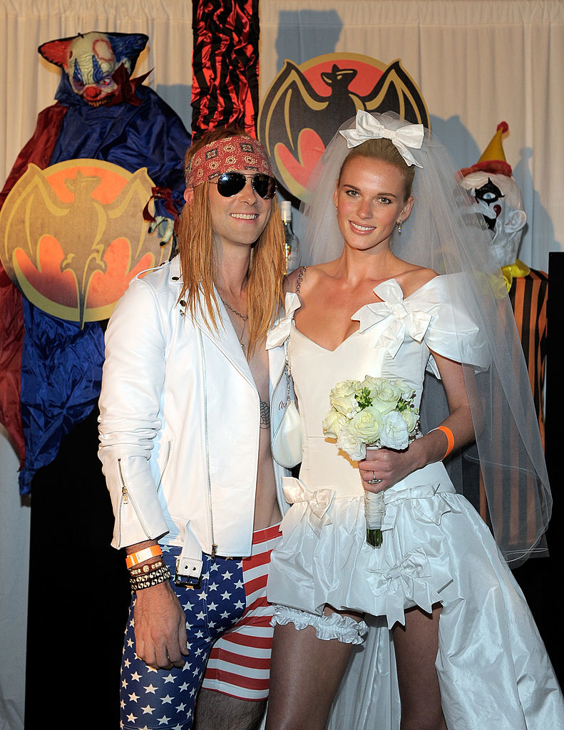 adam in american flag print shorts and a long blonde wig and anne in a short wedding dress