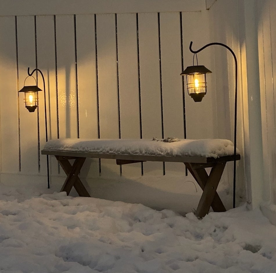 a reviewer photo of the two lanterns next to a bench in the snow