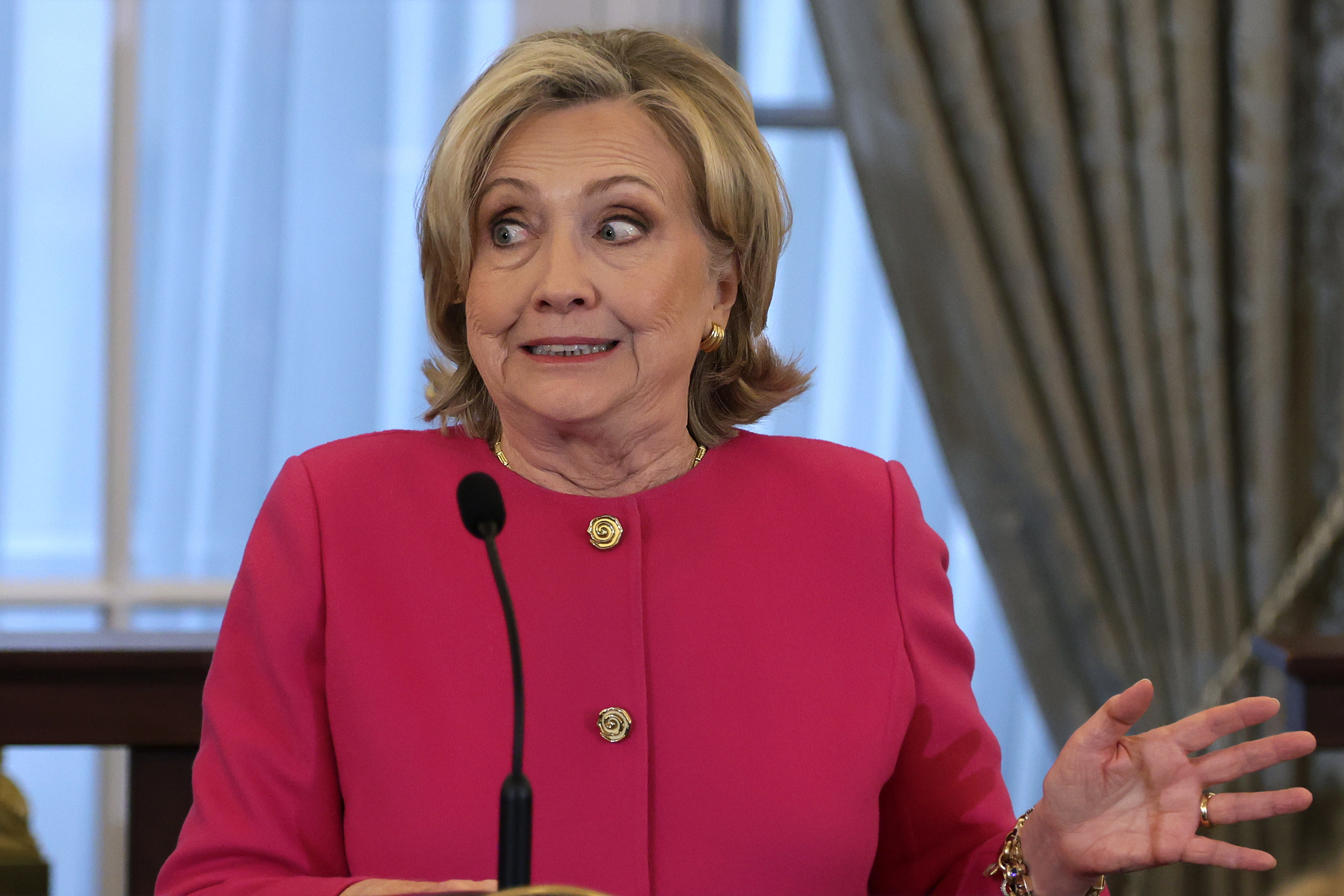 hilary making a yikes face behind the podium