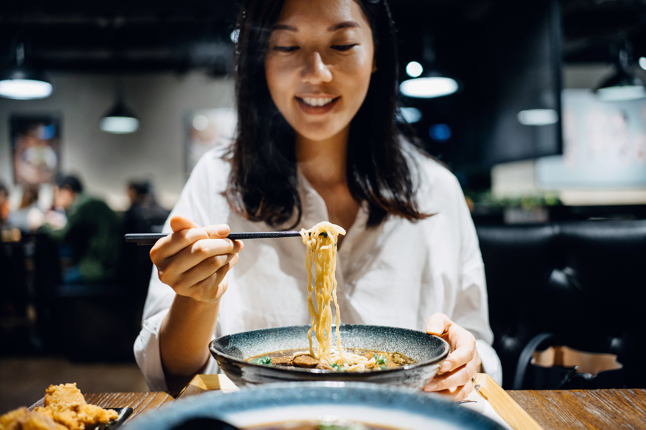 A woman is eating a bowl of noodles