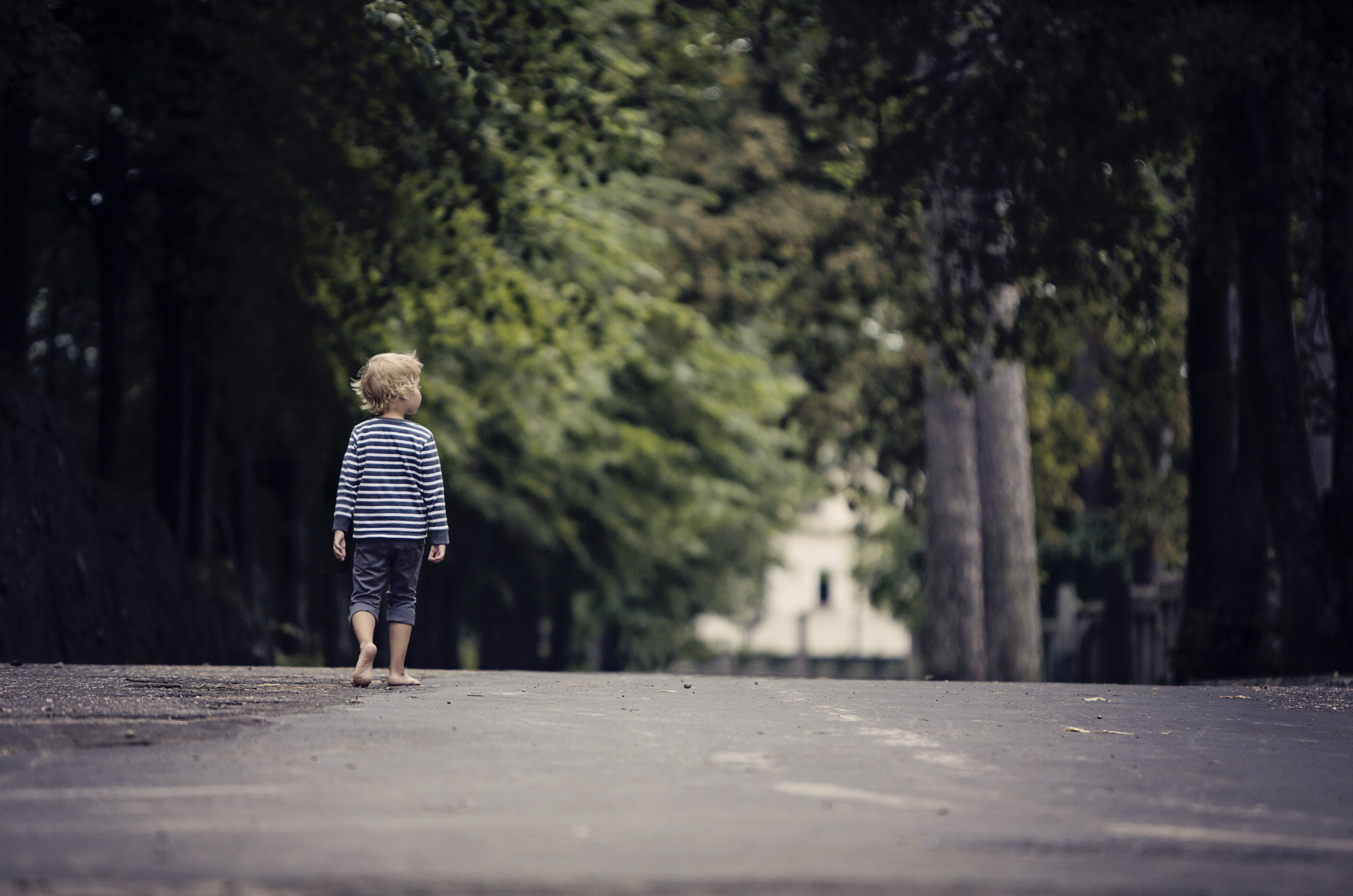 A young boy is walking barefoot in the street