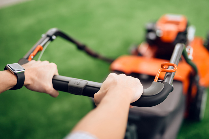 A person&#x27;s hands on a lawnmower