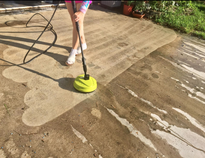 a green pressure washer cleaning up concrete