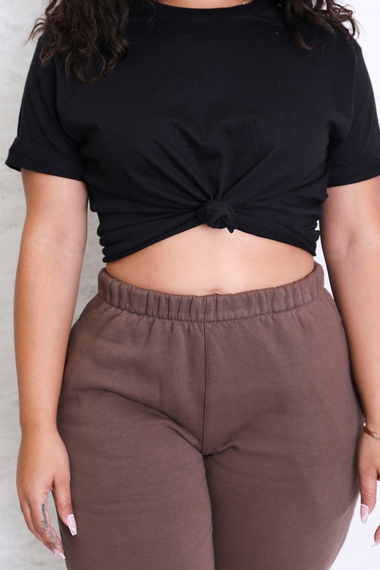 close-up of exemplary  wearing achromatic  knotted harvest  tee with brownish  sweatpants