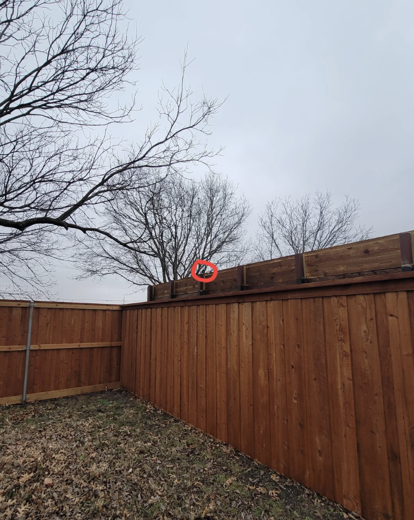 A fence with a camera looking into someone's backyard
