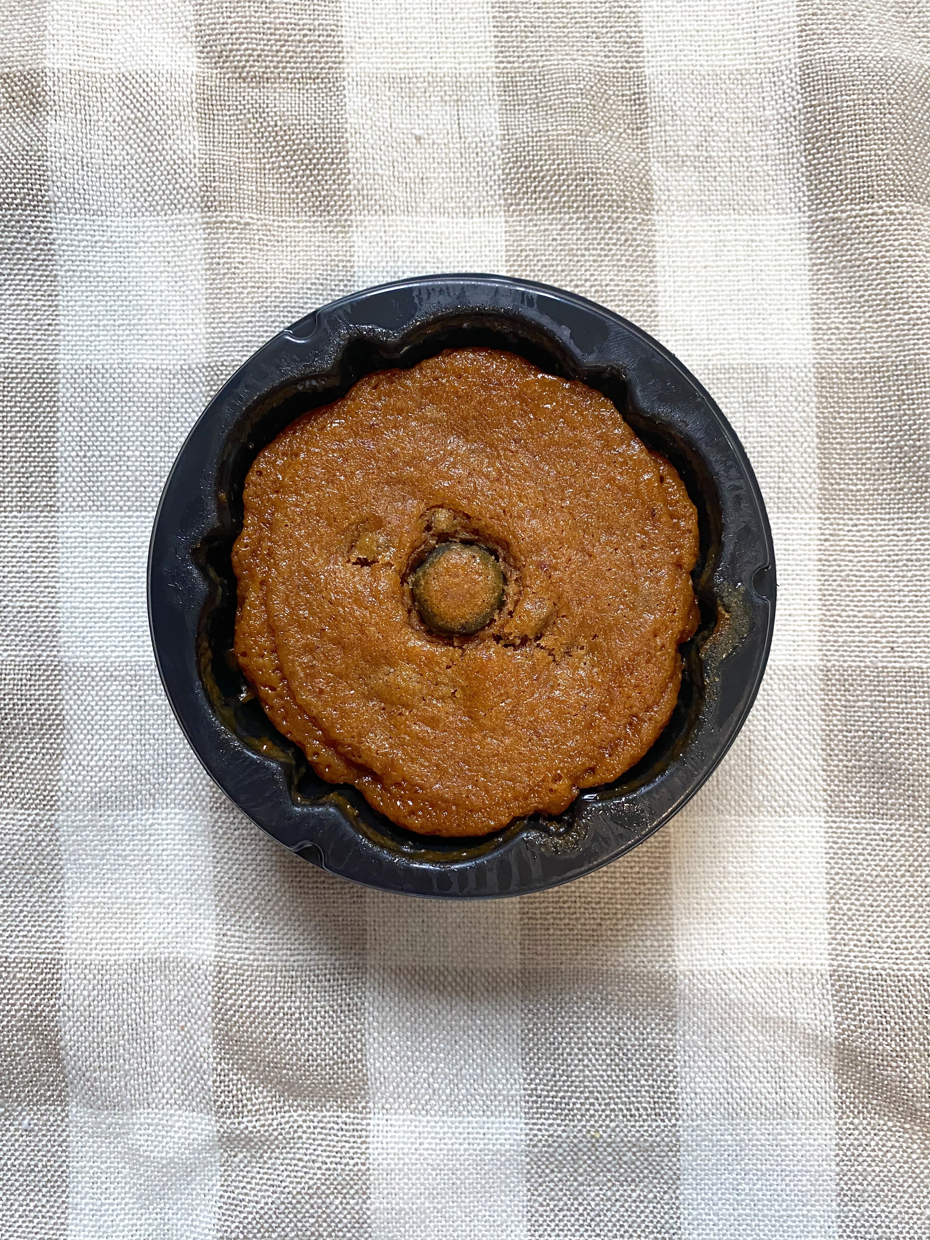 an unpackaged sticky pumpkin toffee cake in a black plastic container