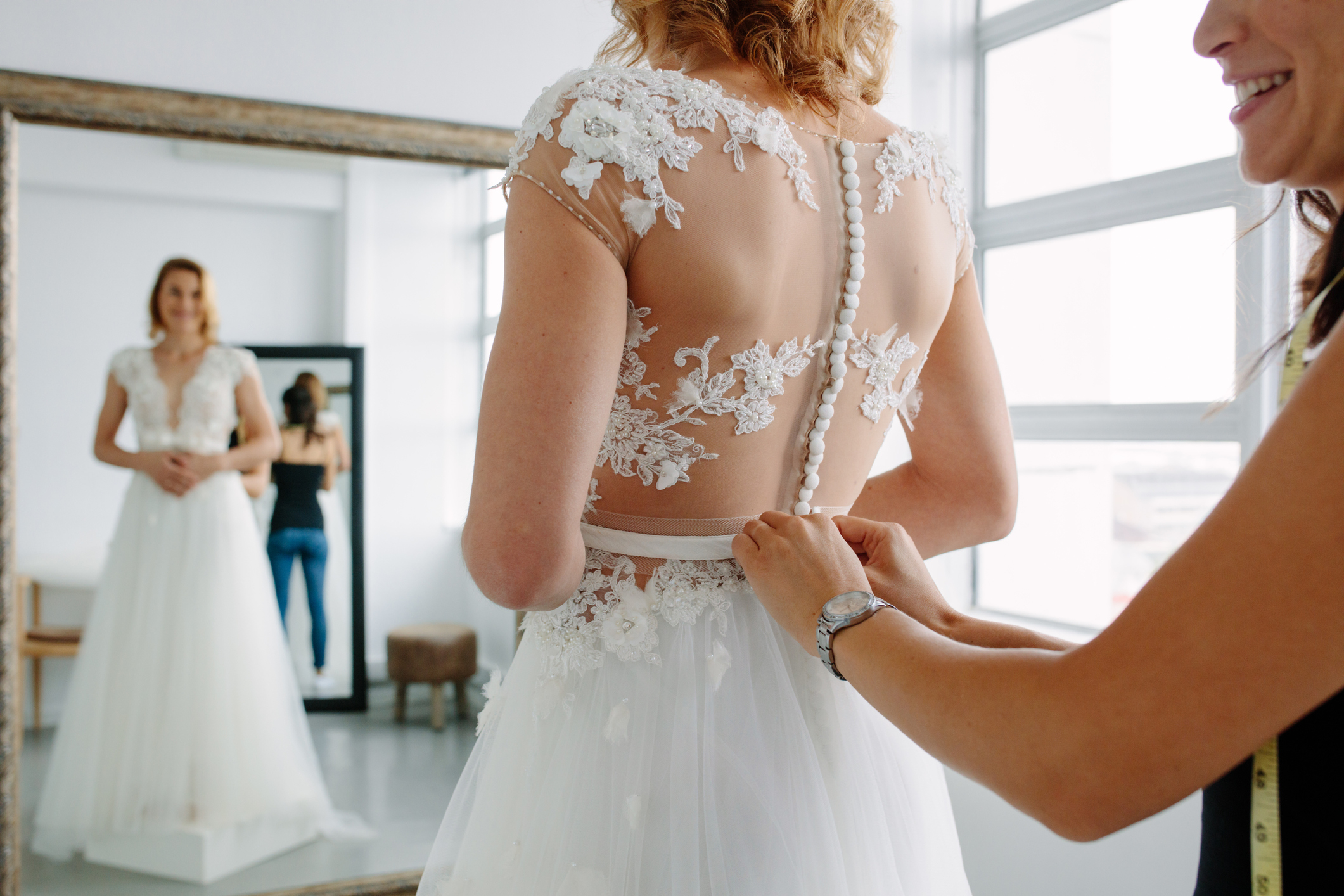 A woman helping a bride put on her wedding dress