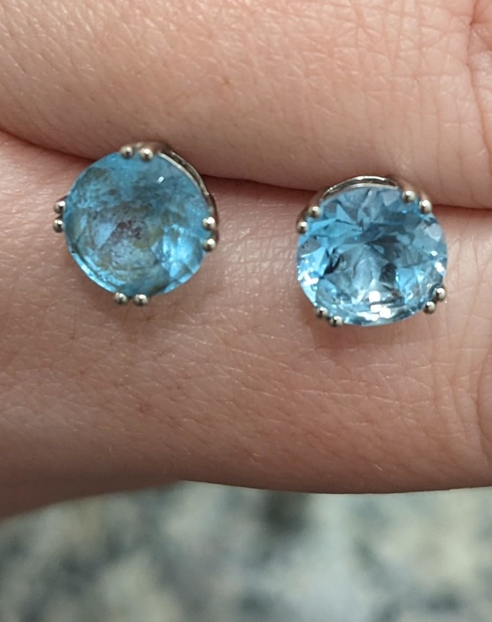 Reviewer holding two blue stone earrings with the right one cleaned with the solution
