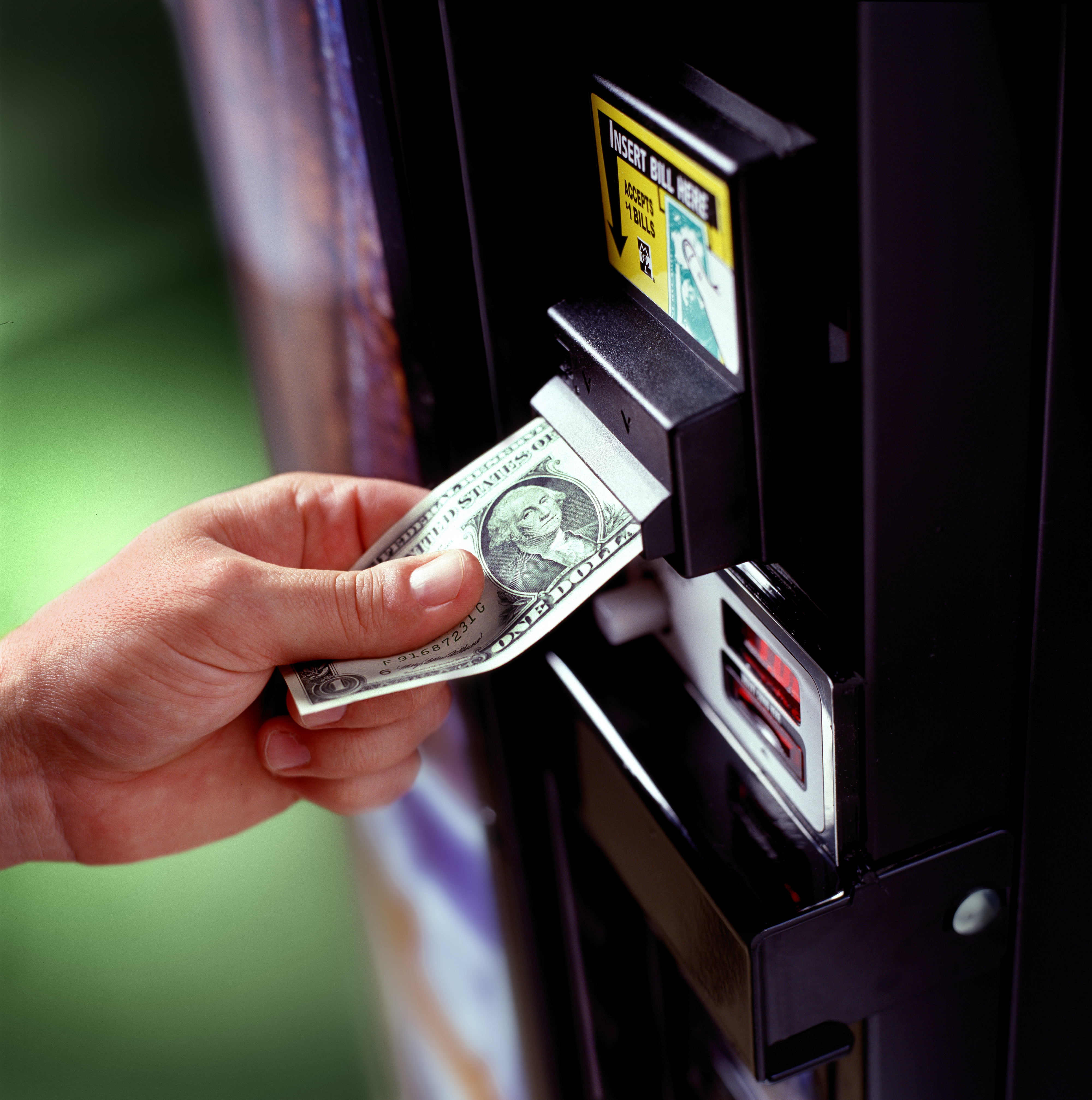 Person putting a dollar in a vending machine