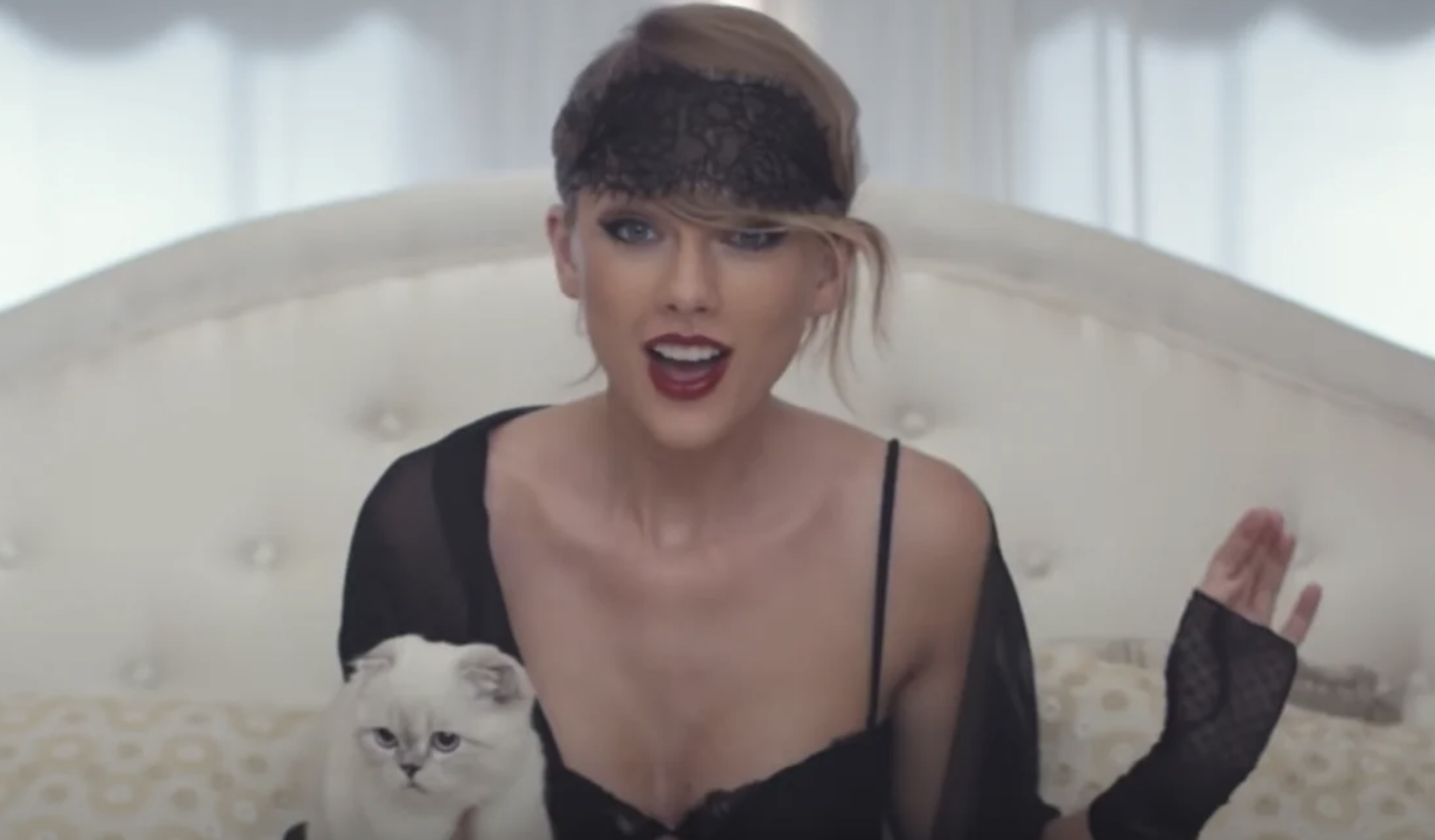 Taylor in the &quot;Blank Space&quot; music video, sitting on a bed while holding her cat.