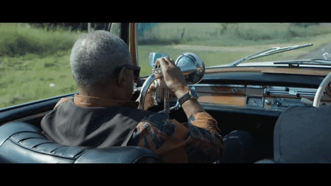 A man is playing the trumpet while driving in his car