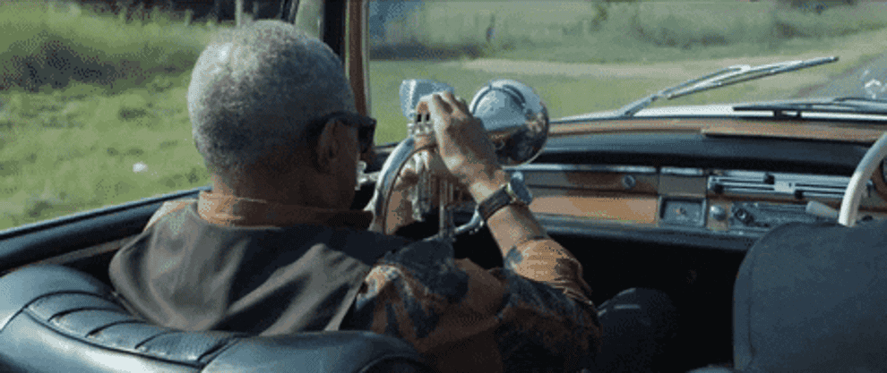 A man is playing the trumpet while driving in his car