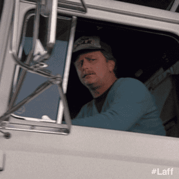 A truck driver is driving by with a shocked look on his face