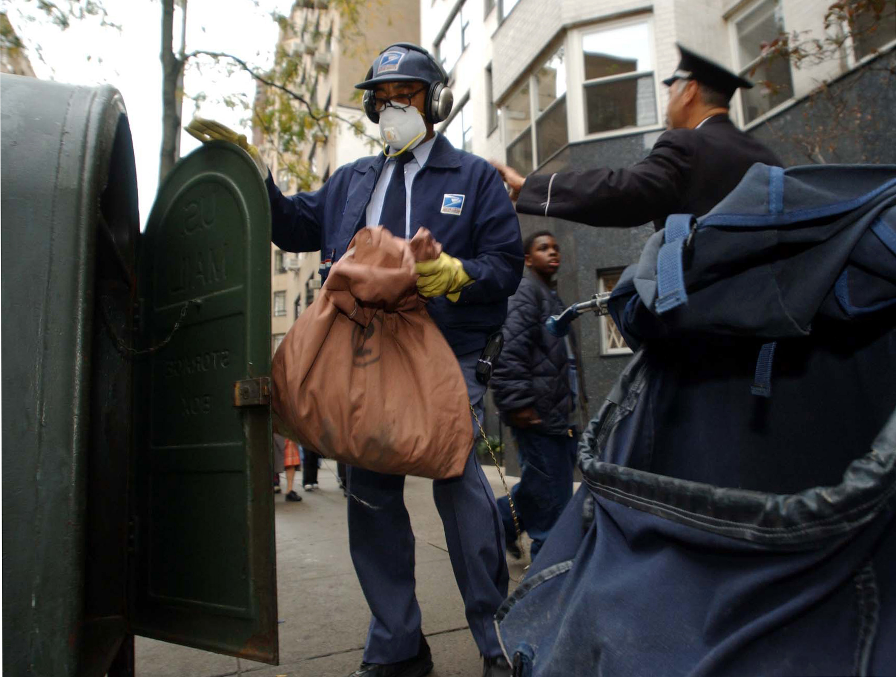 a mail carrier with a mask and gloves on collecting mail