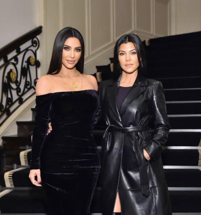 Kim and Kourtney pose for a photo at the bottom of a staircase
