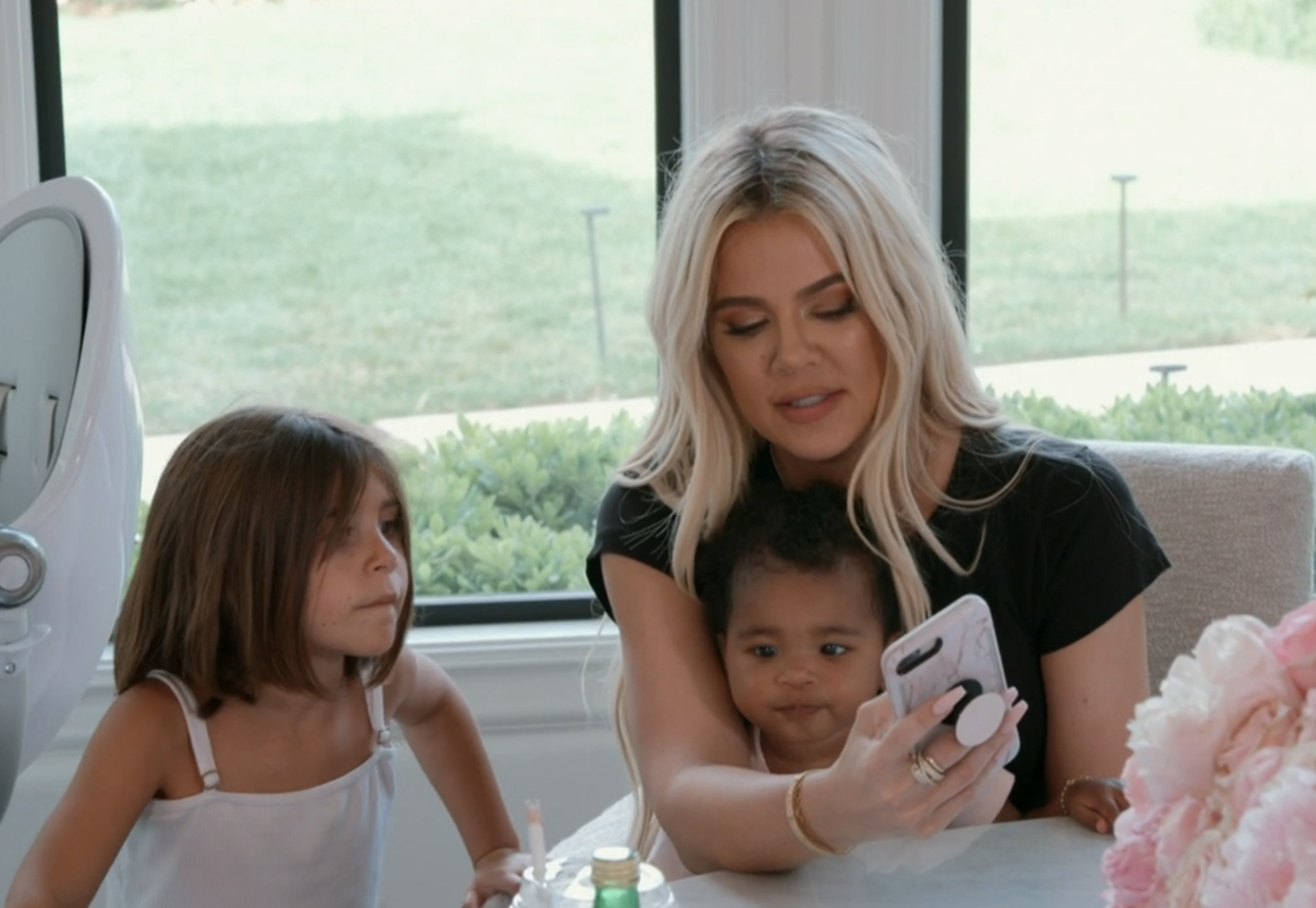 Khloé on the phone and sitting with children