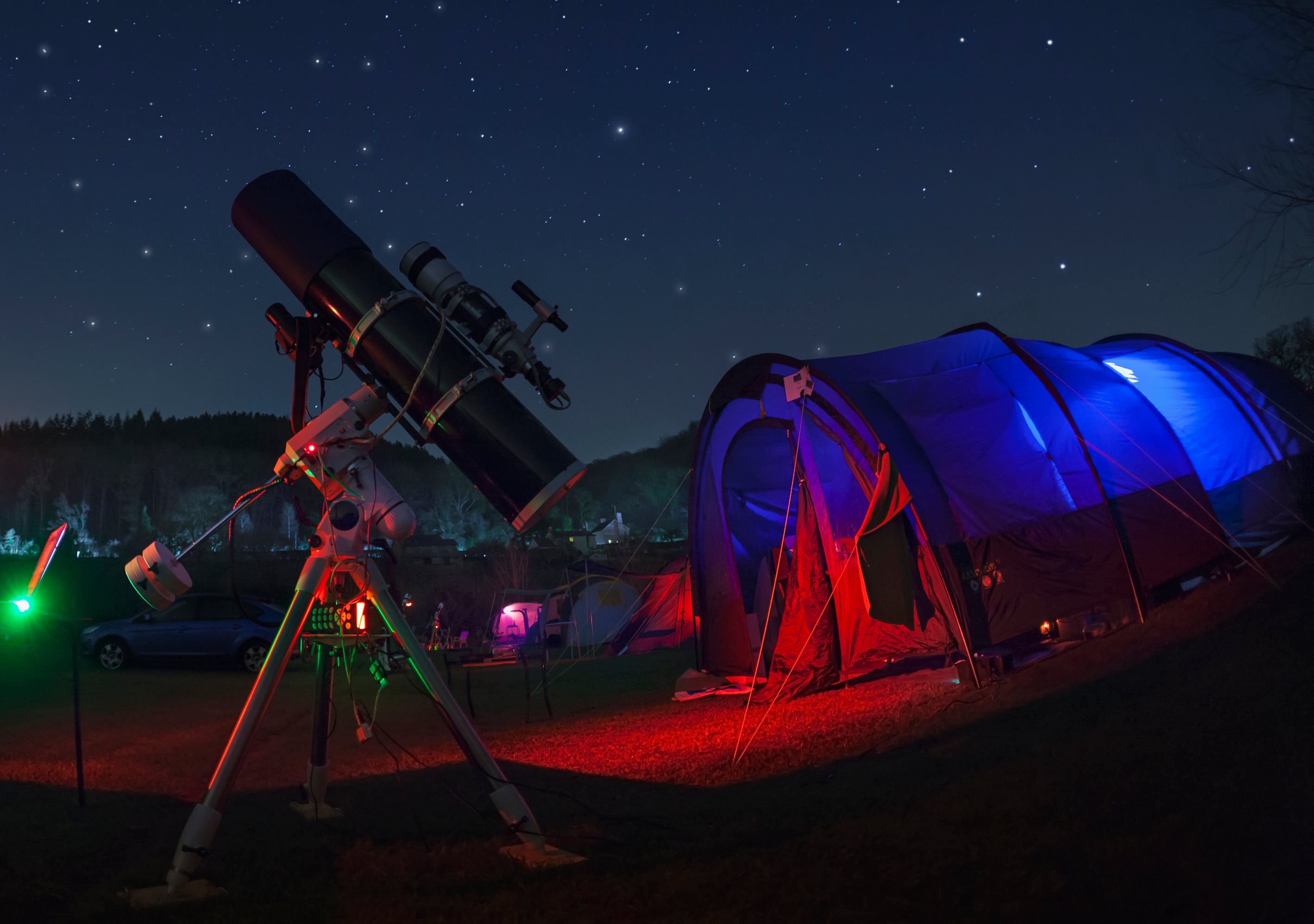 A telescope next to a tent at night