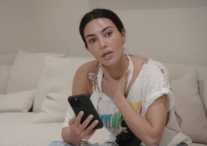 Close-up of Kim sitting on a couch and holding a phone