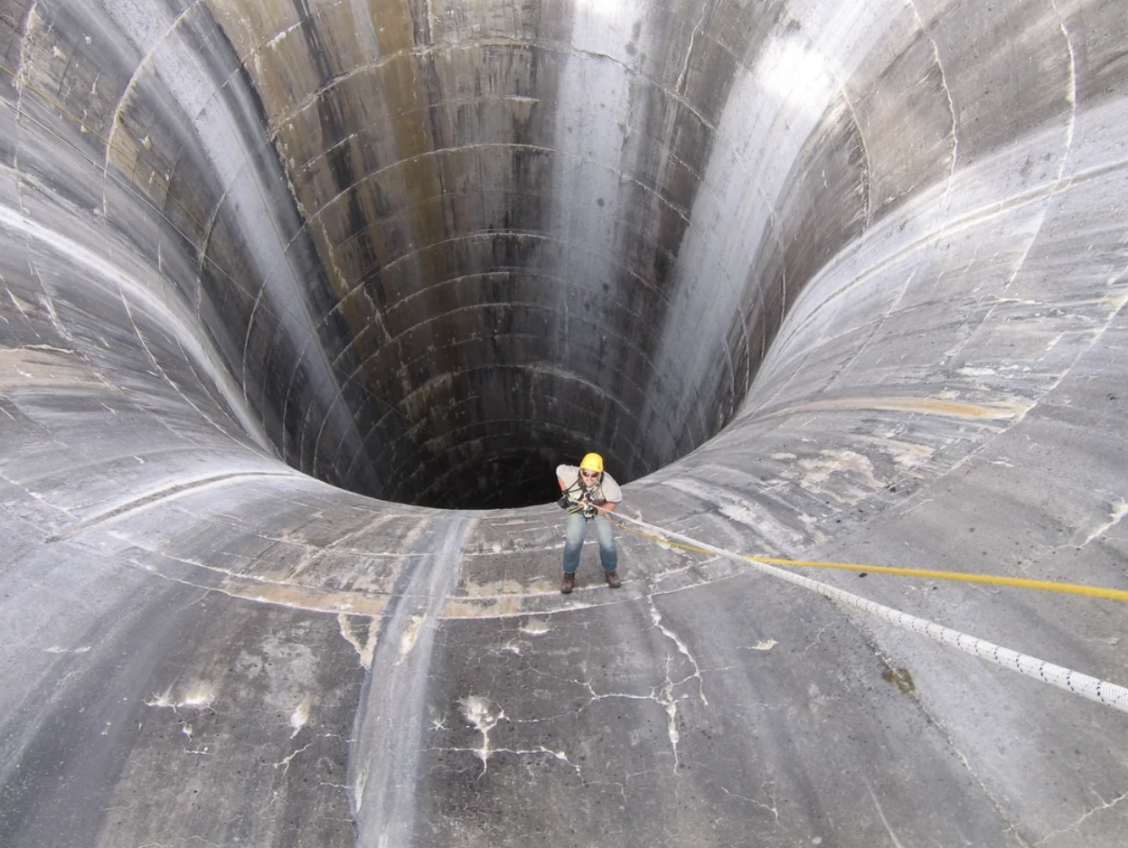 A man spelunking down a massive pipe
