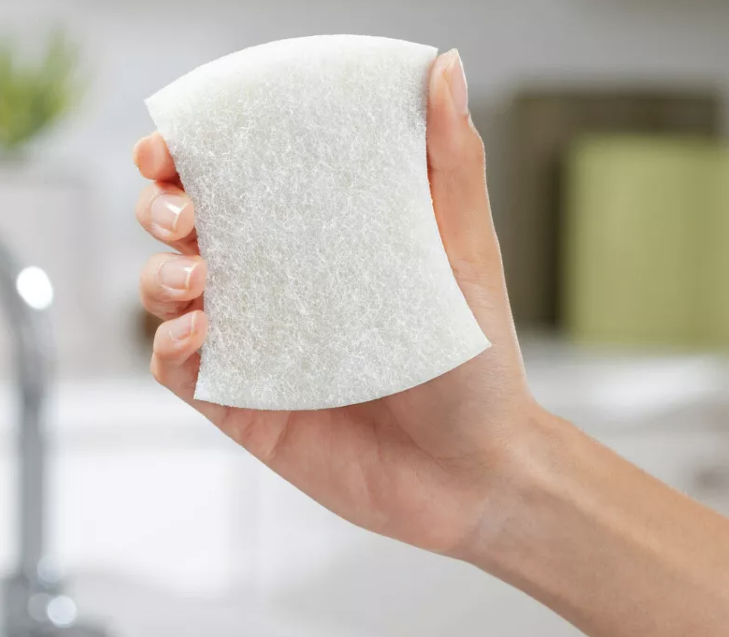 a hand holding a white scrubber
