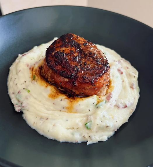 meat on top of mashed potatoes with skins in them