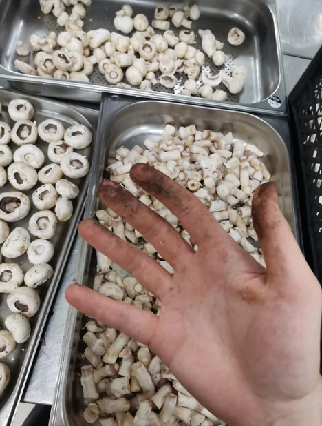 dirty hand while cleaning mushrooms in a kitchen