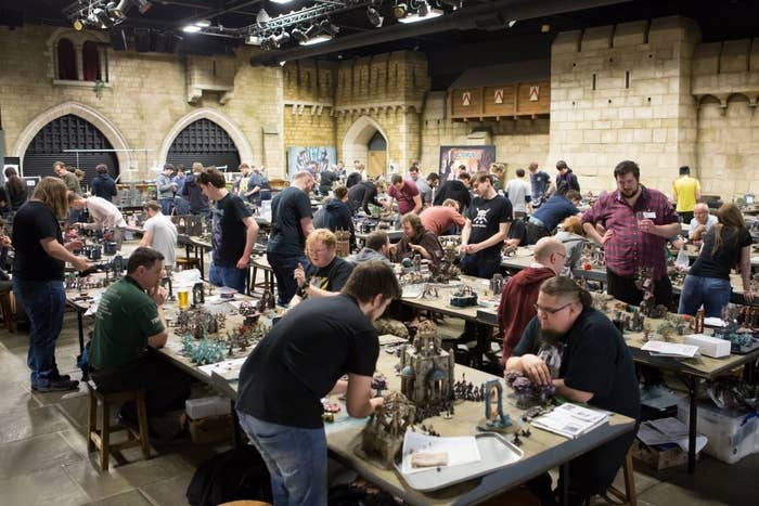 A group of people are playing Warhammer on tables and surrounded by faux castle walls inside Warhammer World in Nottingham