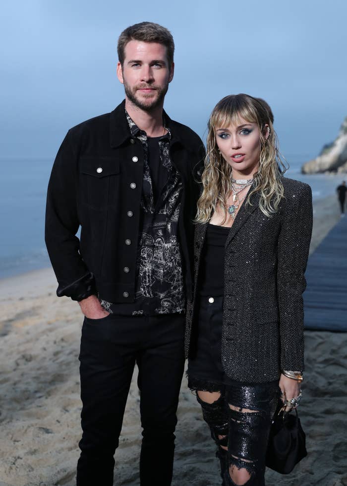 Closeup of Liam Hemsworth and Miley Cyrus standing for a photo at an event