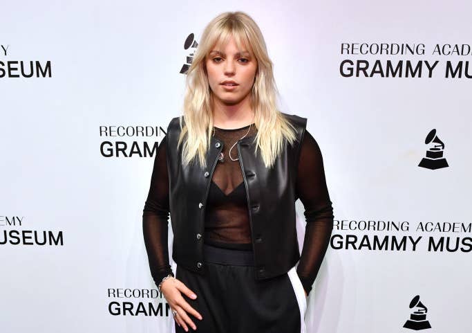 Reneé on the red carpet of a media event wearing a sheer top and leather-like vest with pants