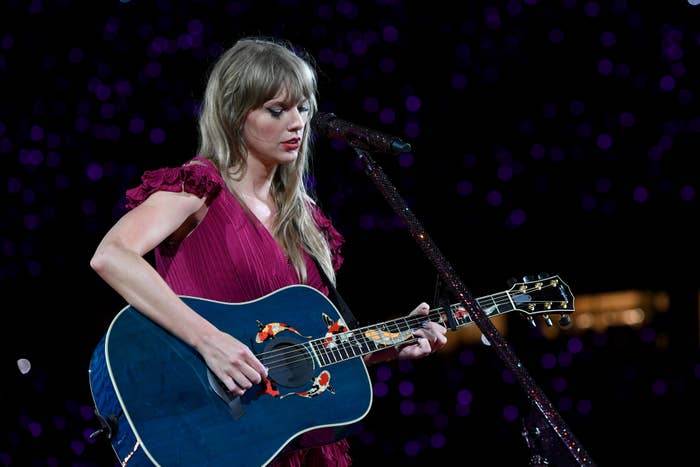 Taylor Swift in a red dress playing a blue guitar