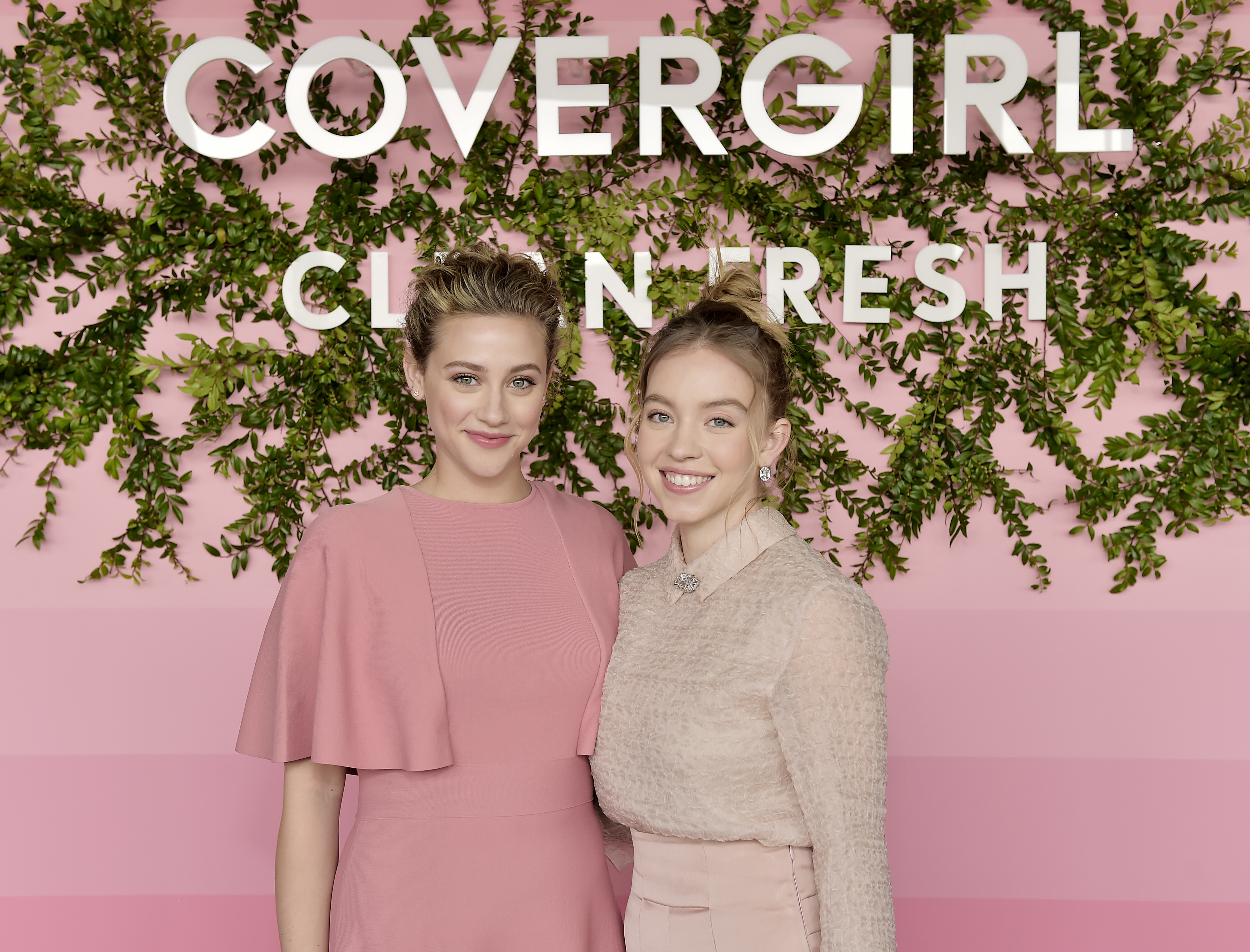 closeup of the two in front of a covergirl backdrop