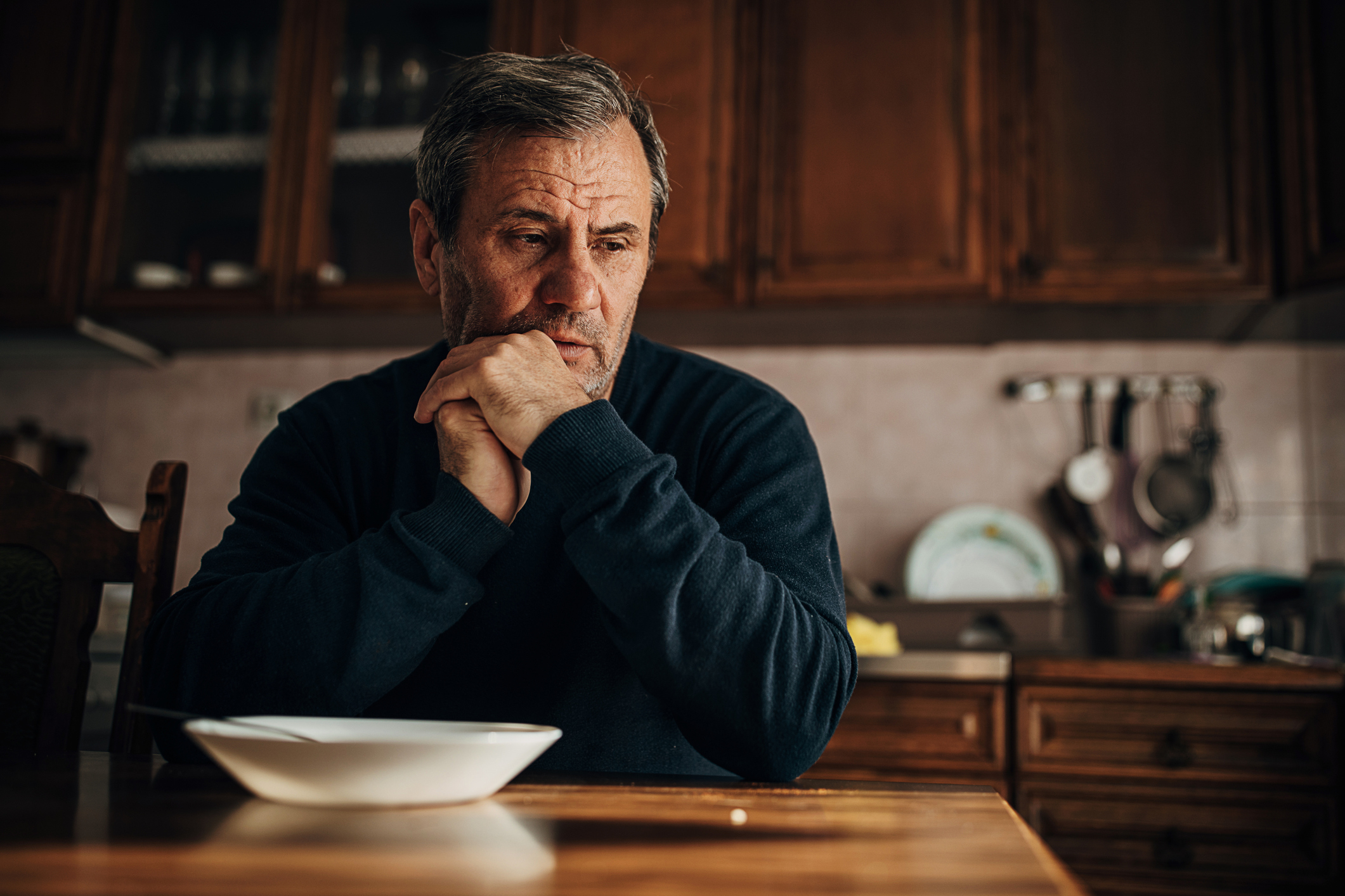 man in the kitchen staring off in thought