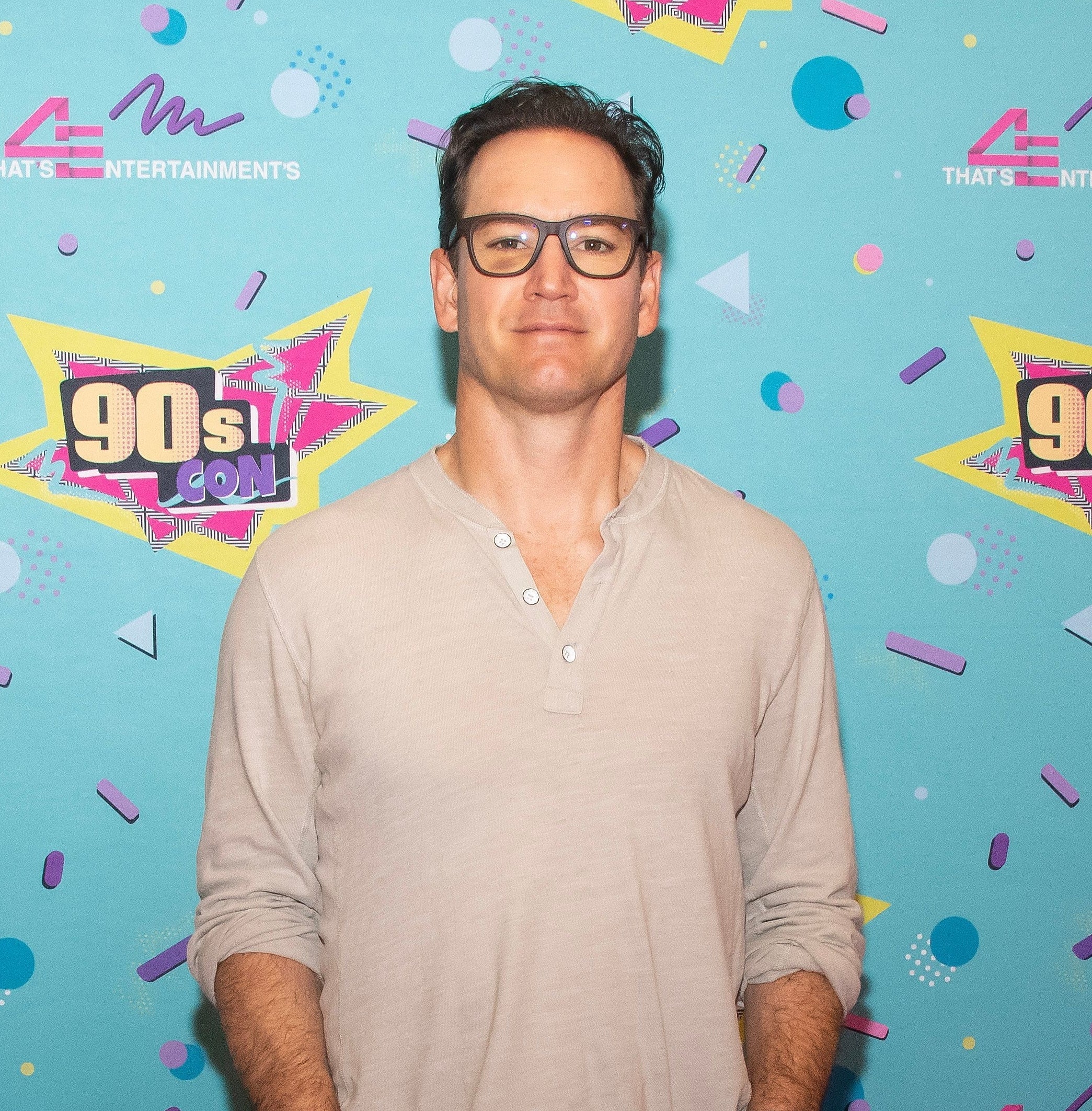 Mark-Paul Gosselaar on the red carpet wearing a Henley shirt and eyeglasses