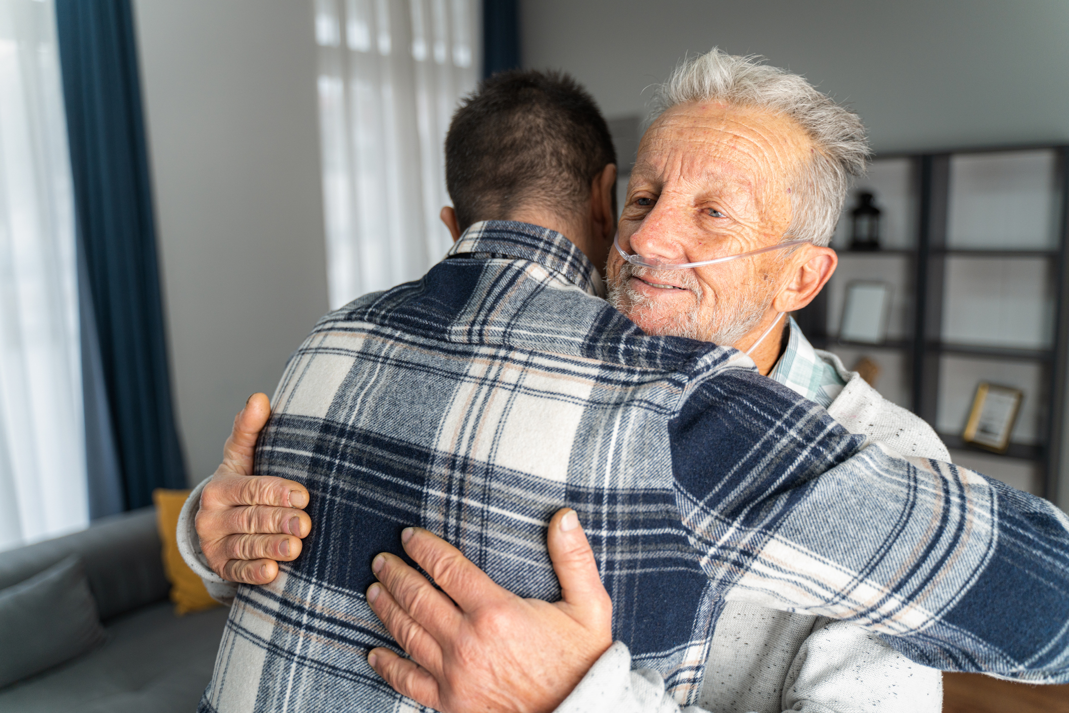 older man hugging someone as they wear tubes to help them breathe