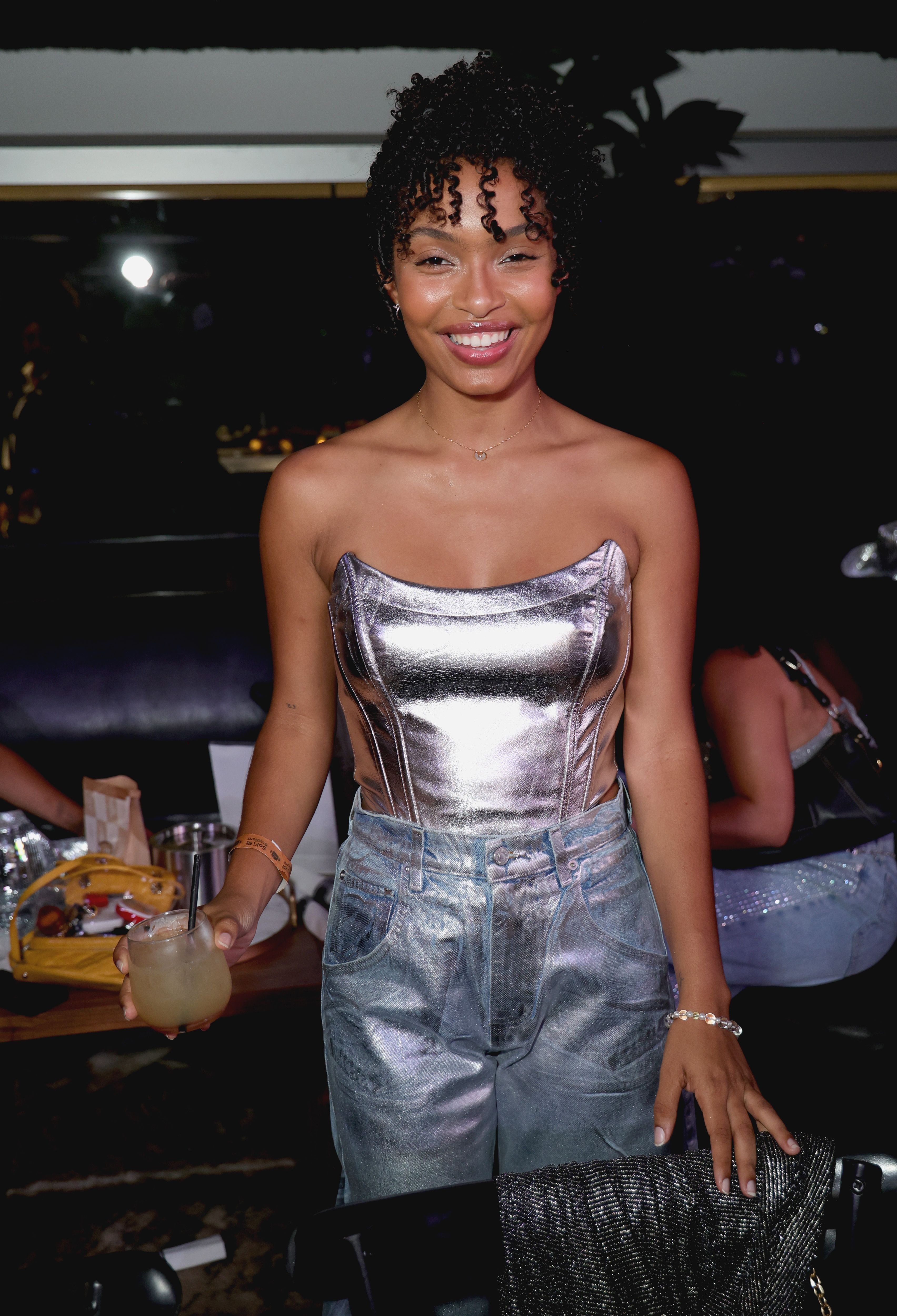 Yara Shahidi smiles for a photo as she holds a drink
