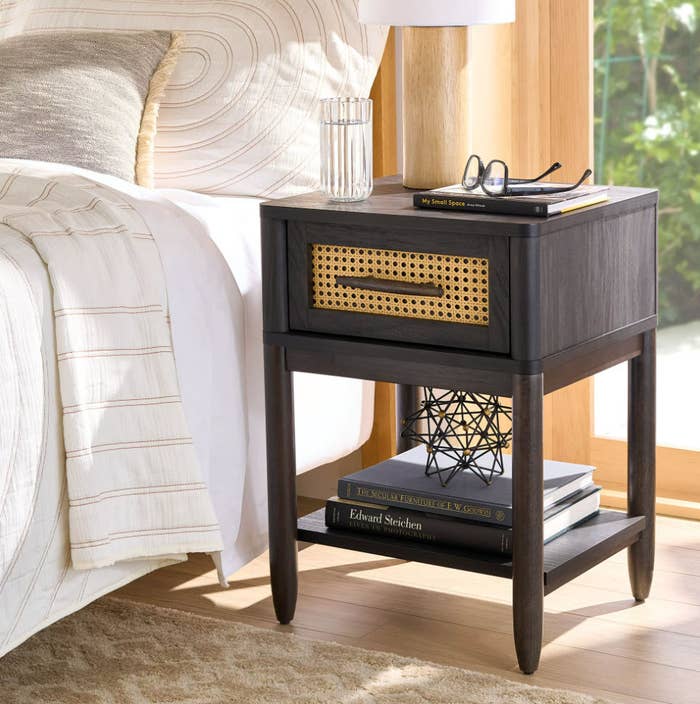 dark black wooden nightstand with drawer next to a bed
