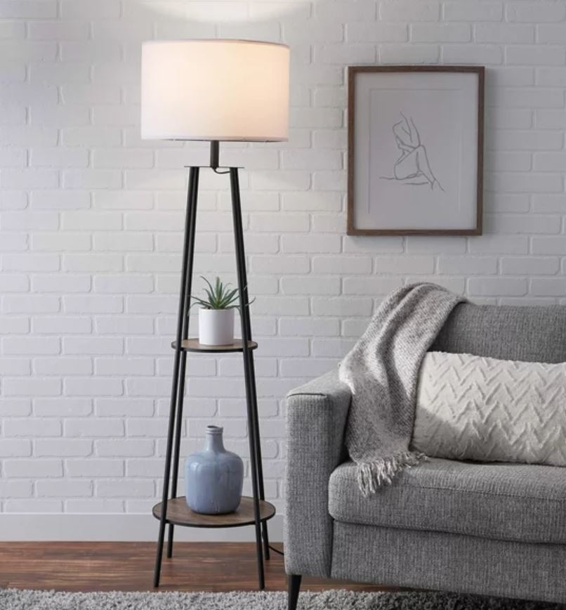standing lamp with two tier shelves next to a couch