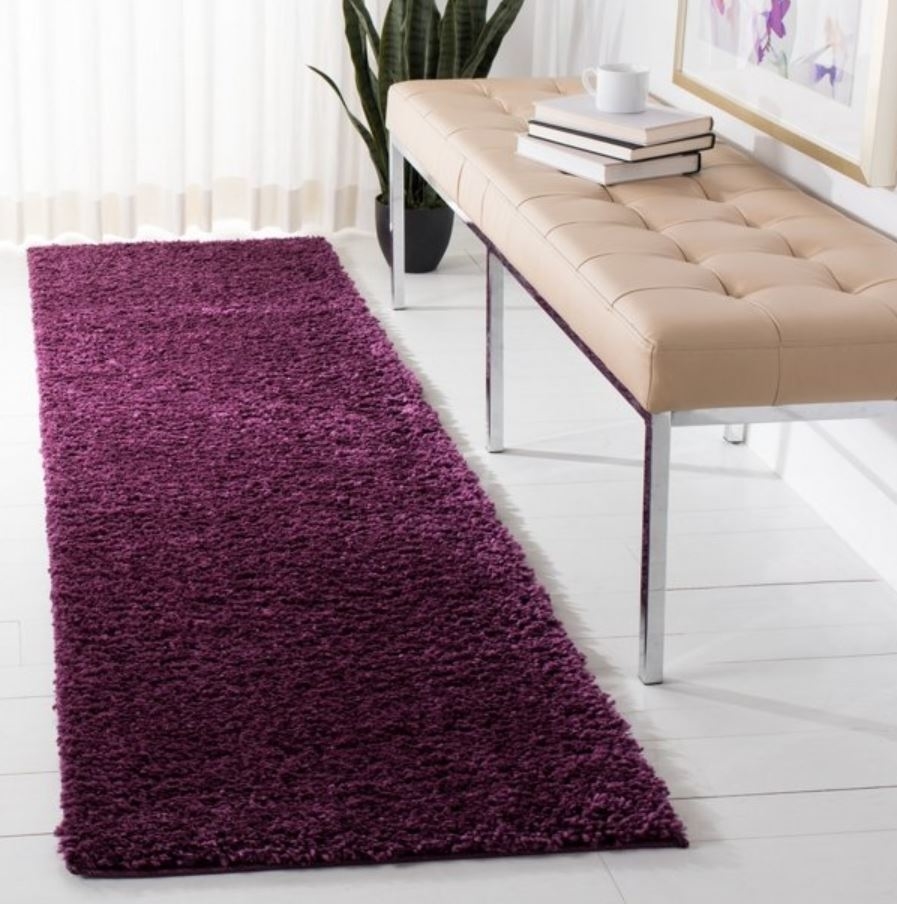 plum colored runner rug next to leather bench