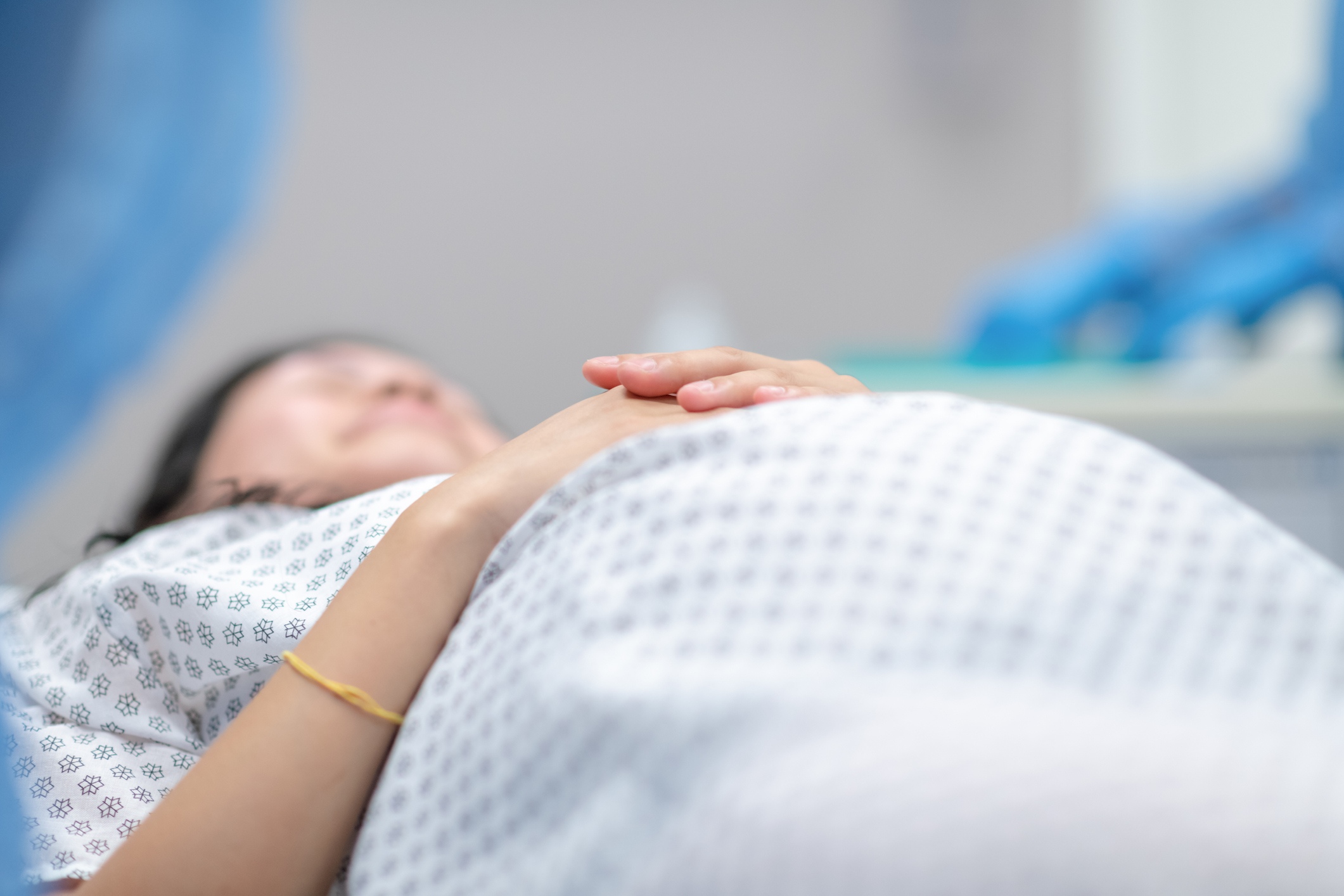 A pregnant woman lying down and wearing a hospital gown