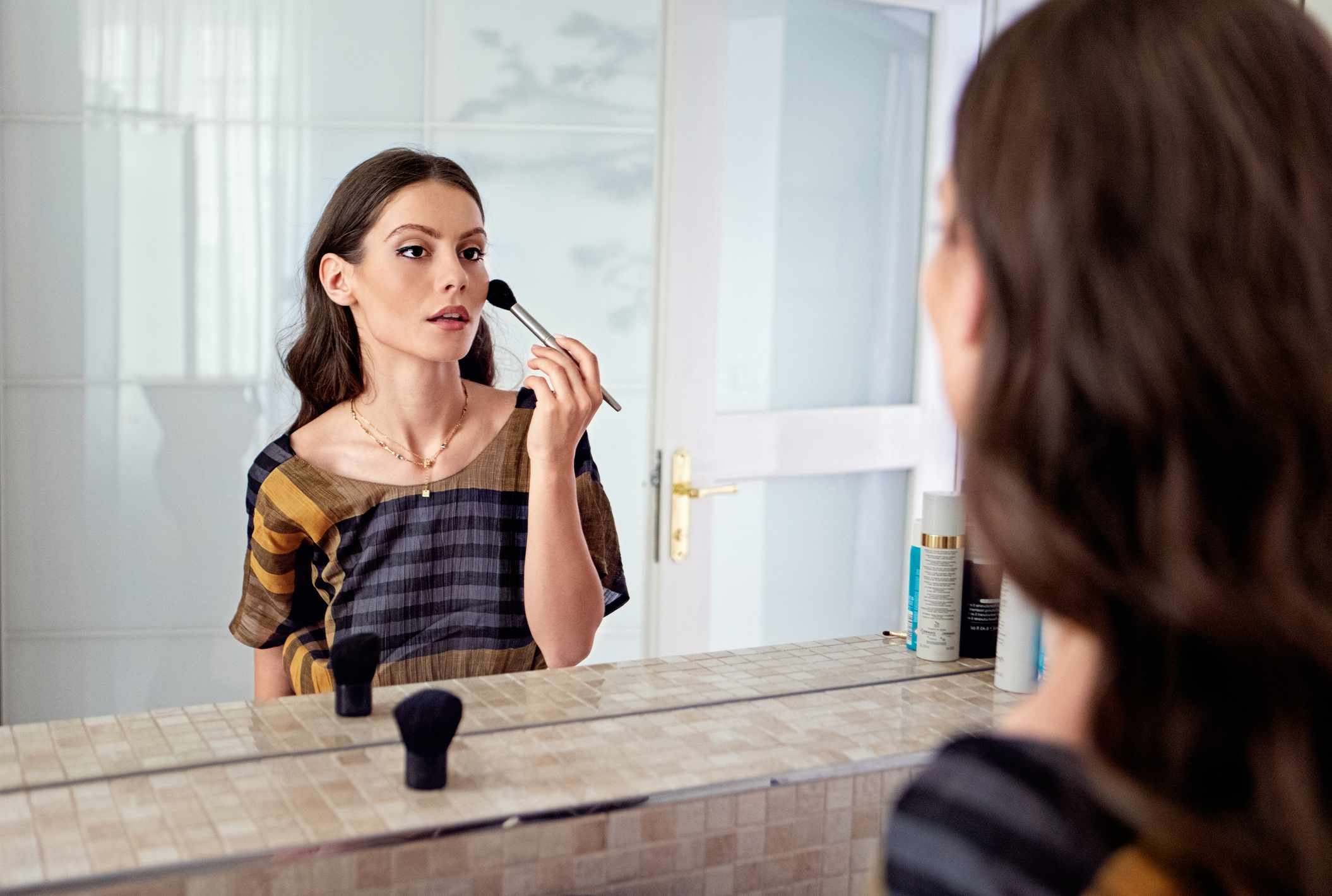 A woman applying makeup in front of a mirror